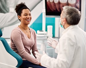 Smiling woman talking to dentist in treatment chair