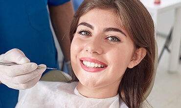 Smiling young female patient in dental chair