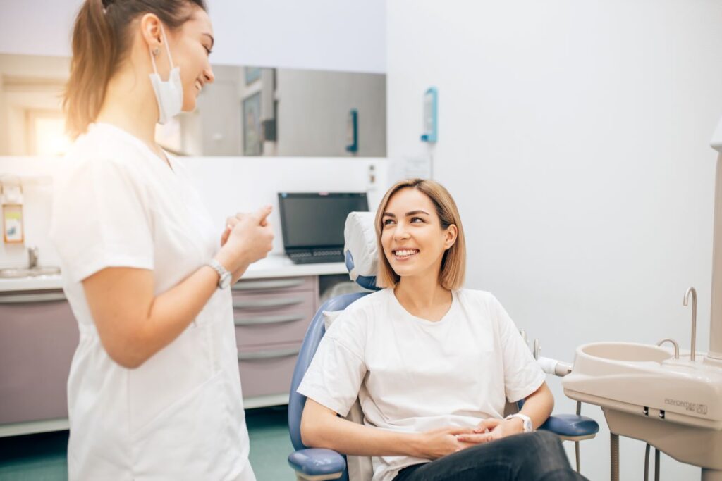 A woman seated in a dentist's chair speaking to a female dentist.