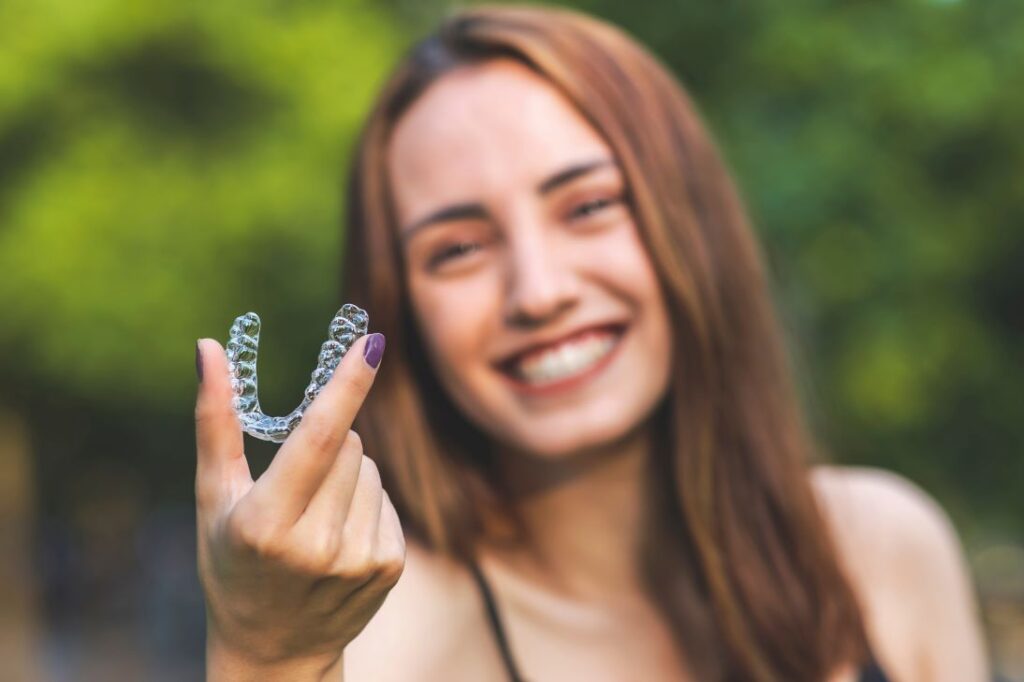 A woman holding an Invisalign aligner